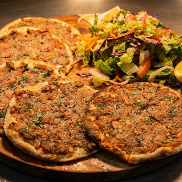 Lahmacun, Turkish flatbreads topped with minced meat and herbs, served with a fresh salad and lemon.